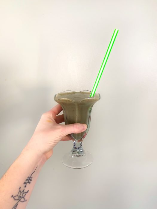 Green CBD shamrock shake in milkshake glass with striped straw for st. patrick's day
