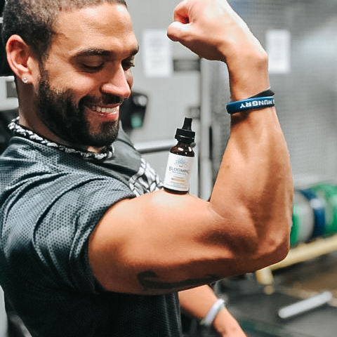 Black man flexing bicep with turmeric tincture on muscle