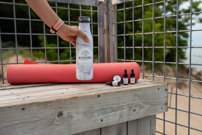 Yoga mat with water bottle and CBD on a beach. 